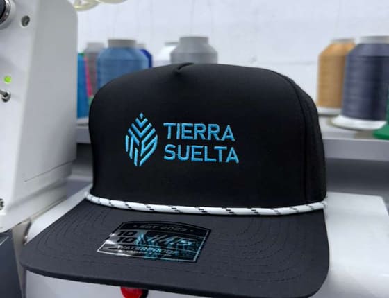 Embroidered brand cap on the embroidery machine, thread cones behind